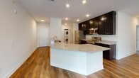 Located at 3730 Evergreen Dr in Monroeville, Pennsylvania, this well-appointed single-floor residence offers a thoughtfully designed open layout with modern finishes throughout. The heart of the home is a stylish kitchen featuring rich dark cabinetry, granite countertops, stainless steel appliances including a refrigerator, range, and microwave, and a central island that flows seamlessly into the open living area. In-unit stacked washer and dryer provide added convenience. The spacious living area is bathed in natural light through large windows and a glass door that opens to a private balcony overlooking lush greenery, complemented by gleaming hardwood-style flooring and recessed lighting. The bedrooms offer a calm retreat with plush carpeting, bright windows with neighborhood views, and neutral tones throughout. The bathrooms are finished with classic black-and-white mosaic tile flooring and brushed nickel fixtures; one includes a soaking tub with a shower combination, while another features a walk-in shower with white tile surround. Clean white walls and crisp trim tie the entire space together, creating a bright, move-in-ready environment with a cohesive and contemporary aesthetic.