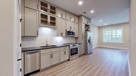 This efficiently designed 590 square foot apartment maximizes space with its open floor plan. The single bedroom, measuring 150 square feet, provides ample personal space. The living area showcases wood-look flooring that extends throughout, creating a seamless and contemporary aesthetic. A standout feature is the large window, which floods the room with natural light and offers views of the surrounding area. The neutral color palette, with beige walls and white trim, contributes to a bright and airy atmosphere. Recessed lighting adds a modern touch while ensuring even illumination. The apartment includes essential spaces such as a bathroom, kitchen, living room, and a closet for storage. Despite its compact size, the thoughtful layout and design elements make this space feel open and inviting, ideal for single occupants or couples seeking a cozy urban dwelling.