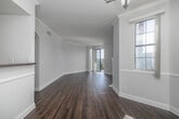 Located on Burton Way in Los Angeles, this 2-bedroom, 2-bathroom residence offers a well-appointed single-floor layout with thoughtful design details throughout. The open living room is a standout, featuring rich hardwood-style flooring, crown molding, and a classic white fireplace with a decorative mantle. A large glass sliding door floods the space with natural light and opens to a private balcony with sweeping views of the tree-lined Los Angeles streetscape, including palm trees and open skies. The kitchen is equipped with dark wood cabinetry, stainless steel appliances including a gas range, over-the-range microwave, and a full-size refrigerator, all set atop warm hardwood-style flooring. The bedrooms are carpeted and bright, with crown molding and steel-framed windows that bring in generous natural light. Five closets are distributed throughout, providing ample storage. The bathrooms feature tile flooring, with one showcasing a stylish vessel sink set on a dark granite countertop atop rich wood cabinetry. Arched hallway details add an elegant architectural touch, tying together the refined aesthetic of this well-designed Los Angeles residence.