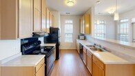 This single-floor residence at 175 Sandbar Ct NE in Rochester, Minnesota, offers a well-organized layout designed for comfortable everyday living. The open-concept kitchen is appointed with light maple cabinetry, black appliances including a range, refrigerator, and dishwasher, and a double-basin sink set beneath windows that allow natural light to fill the space. A peninsula with pendant lighting connects the kitchen to the adjacent dining area, creating a practical and cohesive flow between the two spaces.

The living area features neutral-toned carpet, a ceiling fan with integrated lighting, and windows that bring in additional natural light. A half-wall partition subtly defines the transition between the living and dining zones while maintaining an open feel throughout.

The bedrooms are carpeted and each equipped with ceiling fans. One bedroom includes sliding glass door access to an outdoor balcony, offering views of surrounding greenery. Bedrooms are served by closets with built-in shelving and hanging rods, providing organized storage options.

The bathrooms feature warm hardwood-style flooring, wood-toned vanity cabinetry, and white countertops. Walk-in closet access is conveniently situated adjacent to the bathrooms in multiple areas of the home. The overall palette of warm neutrals and light finishes throughout contributes to a clean, cohesive ambiance.