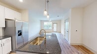 Located at 40 Pallet Rd in Candler, NC, this well-appointed one-bedroom, one-bathroom residence offers a thoughtfully designed single-floor layout with a clean, modern aesthetic throughout. The open-concept kitchen and living area serves as the heart of the home, featuring crisp white shaker-style cabinetry, dark granite countertops, a subway tile backsplash, stainless steel appliances including a refrigerator with ice maker, microwave, and range, as well as a central island with a undermount sink and stylish pendant lighting. Light hardwood-style flooring runs throughout the main living areas, complementing the neutral color palette and ceiling fans that promote airflow and comfort. Natural light filters in through large windows, offering views of the surrounding greenery. The spacious bedroom is finished with plush carpet, a ceiling fan, and a generously sized walk-in closet outfitted with wire shelving for ample storage. A second closet provides additional organizational space. The full bathroom is conveniently accessible, and a private patio extends the living space outdoors. The overall ambiance is bright, clean, and move-in ready, reflecting quality craftsmanship suited for comfortable everyday living.