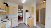 Located at 10620 West 12th Avenue in Spokane, Washington, this single-floor residence offers a well-designed layout with a variety of comfortable living spaces. The living room is a standout area, featuring vaulted ceilings, a skylight, a ceiling fan, and large windows that invite natural light. Floor-to-ceiling mirror panels further enhance the sense of openness and depth in this space.

The kitchen is efficiently laid out with light maple cabinetry, ample counter space, and white appliances including a range, refrigerator, and dishwasher. It opens directly into the dining area, which is illuminated by an elegant chandelier and flows seamlessly toward the living spaces, making it well-suited for entertaining.

The primary bedroom includes plush carpeting and a sliding glass door that opens to a private outdoor deck, offering a quiet retreat with exterior views. Additional bedrooms provide closet storage and natural light through well-placed windows.

Two bathrooms serve the residence: one features a glass-enclosed shower stall with tile surround, while the second includes a full soaking tub with a tiled surround and overhead fixtures. Both bathrooms are finished with tile flooring and light maple cabinetry for overhead storage. Throughout the home, neutral tones and carpet flooring create a cohesive and inviting atmosphere.