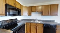 Located on Farmshed Road in Palmyra, Pennsylvania, this two-story residence offers functional living across multiple levels. The kitchen is a standout feature, showcasing warm honey-toned wood cabinetry that extends to the upper walls, providing generous storage space. Dark speckled countertops complement the cabinetry and offer ample prep surface area. The kitchen is equipped with black appliances, including a range, built-in microwave, and dishwasher, creating a cohesive, practical aesthetic. A stainless steel double-basin sink is centrally positioned beneath upper cabinets, adding a clean contrast to the darker tones throughout. The layout is designed with efficiency in mind, utilizing an L-shaped configuration that maximizes workflow and usability. The two-floor layout of the home provides distinct separation between living areas, offering versatility for various living arrangements. The overall design of the space balances practicality with comfort, making it a well-suited home in the Palmyra community of Lebanon County, Pennsylvania.