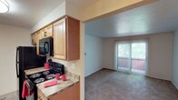 This single-floor residence offers a functional and comfortable layout across its living spaces. The kitchen is designed in a galley style, featuring warm medium-toned wood cabinetry, granite-look laminate countertops, and black appliances including a refrigerator, electric range, and over-the-range microwave. A single-basin sink and tile-style flooring complete the kitchen's practical setup. The kitchen opens directly into the living area, creating a connected feel between the two spaces.

The living room is carpeted and bathed in natural light from a large sliding glass door fitted with vertical blinds, which leads to an outdoor balcony. The open layout provides a versatile space suitable for various furniture arrangements.

The bedroom is generously sized, featuring plush carpeting, a ceiling fan with a light fixture, and notable storage provided by a double bifold closet with full-length hanging rods — offering ample organizational capacity.

The bathroom is accessed via a hallway and includes a wood-toned vanity with an undermount sink, a lighted mirror, tile-look flooring with a striped area rug, and a textured ceiling. The overall ambiance of the space is neutral and move-in ready.