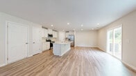 Located in Greenville, SC, this well-designed two-story home offers four bedrooms, three bathrooms, and a thoughtful layout spread across two floors. The main level hosts an open-concept kitchen and living area finished with warm wood-look flooring. The kitchen is a standout, featuring crisp white shaker cabinetry, a light quartz countertop island, a subway tile backsplash, and stainless steel appliances. Natural light filters in through windows fitted with blinds, enhancing the bright, clean aesthetic. An attached garage with a paneled door provides convenient direct-access parking and additional storage. Upstairs, the upper level is the larger of the two floors and accommodates the bedrooms, including a generously sized primary suite with its own closet. The additional bedrooms are carpeted and well-lit, sharing access to the remaining bathrooms, which feature wood-look tile flooring, white vanities, and tub-shower combinations. A dedicated laundry room is equipped with a full-size washer and dryer and wire shelving above. Closets throughout offer wire-rack storage systems, maximizing organization. The home's neutral color palette, consistent finishes, and practical floor plan make it a functional and comfortable residence.