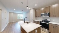 Located at 196 Westfield Rd in Noblesville, Indiana, this well-designed one-bedroom, one-bathroom residence offers a thoughtfully organized single-floor layout. The open-concept kitchen and living area serves as the heart of the home, featuring light wood-tone cabinetry, stainless steel appliances, a tile backsplash, and a central island with a white countertop and pendant lighting — an ideal setup for both cooking and entertaining. Warm hardwood-style flooring flows throughout the main living areas, lending a clean, contemporary feel. The living room provides a bright, open canvas with recessed lighting and neutral walls. The bedroom is a comfortable retreat finished with plush carpet, a ceiling fan, and a window that brings in natural light and outdoor views. A spacious walk-in closet with wire shelving offers generous storage. The bathroom is finished with wood-toned cabinetry, a white countertop vanity with matte black fixtures, wood-look tile flooring, and a glass-enclosed shower. A hallway connects the living spaces efficiently, completing a cohesive and functional floor plan suited for modern living.