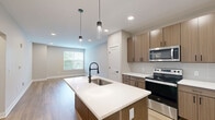 Located at 196 Westfield Rd in Noblesville, Indiana, this well-designed one-bedroom, one-bathroom residence offers a thoughtfully organized single-floor layout. The open-concept kitchen and living area serves as the heart of the home, featuring light wood-tone cabinetry, stainless steel appliances, a tile backsplash, and a central island with a white countertop and pendant lighting — an ideal setup for both cooking and entertaining. Warm hardwood-style flooring flows throughout the main living areas, lending a clean, contemporary feel. The living room provides a bright, open canvas with recessed lighting and neutral walls. The bedroom is a comfortable retreat finished with plush carpet, a ceiling fan, and a window that brings in natural light and outdoor views. A spacious walk-in closet with wire shelving offers generous storage. The bathroom is finished with wood-toned cabinetry, a white countertop vanity with matte black fixtures, wood-look tile flooring, and a glass-enclosed shower. A hallway connects the living spaces efficiently, completing a cohesive and functional floor plan suited for modern living.