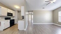 Located at 1625 Sunset Dr in San Angelo, TX, this single-story, 3-bedroom, 2-bathroom home offers a functional and comfortable layout with clean, neutral finishes throughout. The open-concept kitchen and living area form the heart of the home, featuring light hardwood-style flooring, warm taupe walls, and white trim. The kitchen is equipped with white cabinetry, light stone countertops, black appliances including a range and over-the-range microwave, a stainless steel refrigerator, and a double sink set into a peninsula that separates the kitchen from the living space. A ceiling fan in the living area adds to the comfortable atmosphere. The spacious primary bedroom boasts vaulted ceilings, two windows that invite natural light, hardwood-style flooring, a ceiling fan, and a built-in closet. The two additional bedrooms feature plush carpeting, ceiling fans, natural light from windows, and closet access. Both bathrooms are well-appointed, one with a white vanity, light stone countertop, and stylish overhead lighting, while the second includes a full tub and shower surround. A central hallway connects all rooms efficiently. The home presents a clean, move-in-ready aesthetic throughout.
