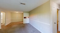 Located at 600 Holiday Cir in Forsyth, Georgia, this single-floor residence offers 2 bedrooms and 3 bathrooms within a practical and comfortable layout. The combined kitchen and living room serves as the heart of the home, with the living area featuring plush carpeting, neutral-toned walls with chair rail molding, and a sliding glass door that opens to a wooden deck overlooking a lush, tree-lined backyard. The galley-style kitchen is well-appointed with white cabinetry, granite-look countertops, a stainless steel sink, and black appliances including a refrigerator, range, and dishwasher, all set atop light hardwood-style flooring. Both bedrooms are carpeted and bathed in natural light from windows with views of the surrounding greenery. The primary bedroom includes a ceiling fan with light fixture and a closet with bifold doors. The bathrooms feature tub/shower combinations and vanities with granite-look countertops. A hallway and dedicated closet round out the interior. Textured ceilings are found throughout, adding a classic touch to the home's overall warm and functional ambiance.