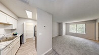 Located at 100 Bent Tree Dr in Daytona Beach, Florida, this 2-bedroom, 2-bathroom residence offers a well-organized single-floor layout designed for comfortable everyday living. The open-concept living and dining area features neutral gray carpeting, a textured ceiling, and a ceiling fan, creating a bright and airy atmosphere. A large window at the far end of the living room allows natural light to filter in, offering pleasant outdoor views of surrounding greenery. The kitchen is equipped with white cabinetry, a stainless steel sink, and wood-look vinyl flooring that extends through the main corridor, providing a clean contrast to the carpeted living spaces. A skylight above the kitchen area adds an additional source of natural light. Both bedrooms are carpeted and include ceiling fans, windows with vertical blinds, and access to closet space. The primary bedroom is generously sized and connects to a dedicated closet. Each bathroom features a full tub-shower combo with clean white surrounds and wood-look flooring. A dedicated laundry area with a full-size washer and dryer and wire shelving adds everyday convenience. Additional storage is provided through multiple closets and a pantry. The unit also includes a private balcony, offering outdoor access.