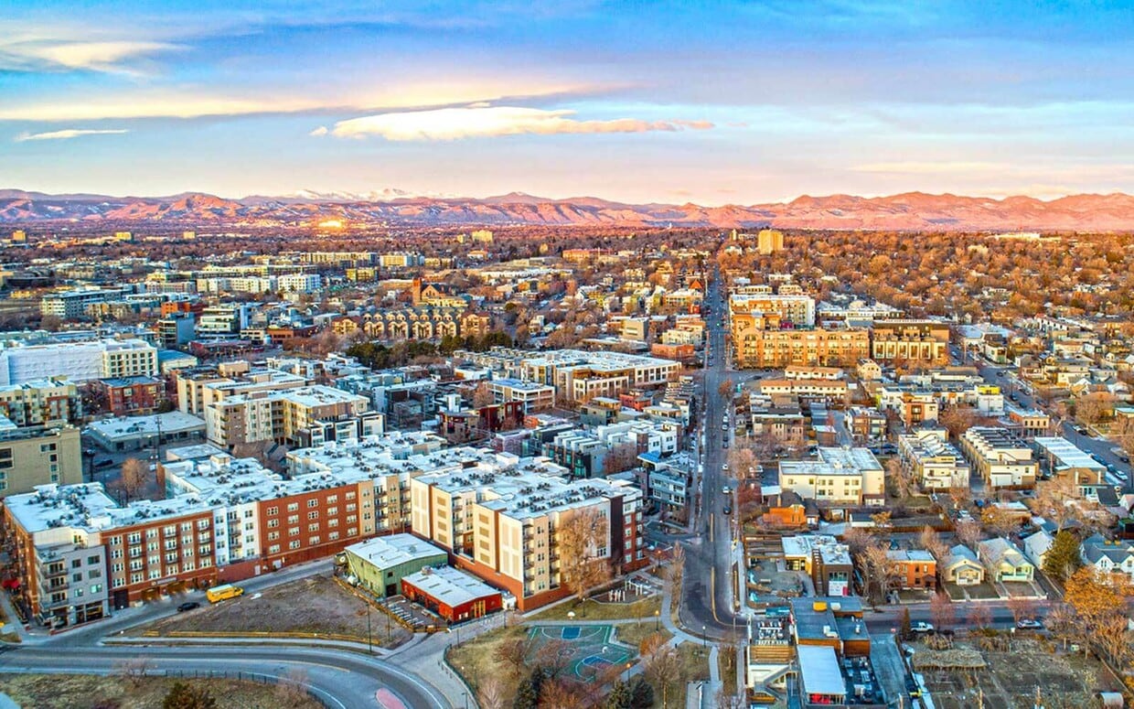 Breathtaking aerial view of a vibrant cityscape, showcasing a harmonious blend of urban architecture and scenic mountain backdrop at sunset. - Bonneville Apts