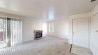 Located in Palmdale, CA, this single-story, one-bedroom, two-bathroom home offers a well-organized layout with a comfortable and functional design. The spacious living room is a standout feature, anchored by a classic brick fireplace with a glass-front surround and plush wall-to-wall carpeting. Natural light filters in through multiple windows fitted with blinds, lending a bright and airy feel. Sliding glass doors open to a private balcony, seamlessly connecting indoor and outdoor living. The galley-style kitchen is efficiently designed with warm oak-trimmed white cabinetry lining both sides, light wood-look flooring, white appliances including a gas range and refrigerator, and a ceiling fan overhead. It opens directly to the dining area, making the space ideal for everyday living. The bedroom is generously sized with soft carpeting and features a sliding-door closet with built-in shelving, and direct access to a bathroom. Two full bathrooms serve the home — one with a tub/shower combination and one with a vanity and mirror cabinet. Additional storage is provided by four closets distributed throughout. A hallway ties each area of the home together in a cohesive and practical floor plan.