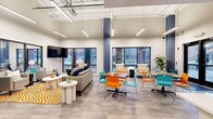 Located at 430 Indiana Ave, this single-floor amenity space offers a thoughtfully designed layout across a generous footprint, combining social, functional, and fitness areas under one roof. The open lounge and dining area serves as the heart of the space, boasting soaring ceilings with exposed industrial-style ductwork, sleek linear pendant lighting, and large floor-to-ceiling windows that flood the interior with natural light and frame views of the surrounding neighborhood. Vibrant teal and navy accent walls punctuate the bright, neutral palette, while colorful furnishings in orange and turquoise lend an energetic, contemporary feel. A kitchenette with white cabinetry and stainless steel appliances supports the lounge and dining zone. The dedicated exercise room is well-equipped with cardio machines and benefits from expansive windows overlooking the outdoors. Two private meeting rooms feature warm wood conference tables, modern circular pendant lights, mounted displays, and whiteboards — ideal for collaborative work. Connecting hallways are neatly furnished with seating and decorative accents. Throughout the space, patterned carpeting and durable hard flooring define each zone, contributing to a cohesive, polished, and welcoming environment.
