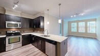 Located at 12190 Waveland St in Fairfax, VA, this thoughtfully designed 2-bedroom, 2-bathroom residence offers a comfortable and functional single-floor layout. The open-concept kitchen and living area serves as the heart of the home, showcasing rich dark cabinetry with sleek hardware, light granite countertops, a tile backsplash, and stainless steel appliances. A peninsula with pendant lighting provides additional prep space and doubles as a casual dining area. Light hardwood-style flooring extends throughout the main living spaces, complemented by crown molding that adds a refined touch. The living room benefits from natural light through a large window with exterior views of the surrounding neighborhood. Both bedrooms feature plush carpeting, neutral warm-toned walls, and windows that invite natural light. The primary bathroom is well-appointed with a dual-sink vanity, dark cabinetry, granite countertops, a large mirror, and a tub-shower combination with tiled surround. The second bathroom mirrors the same quality finishes. A walk-in closet with wire shelving systems provides generous storage. Additional highlights include built-in shelving in the living area, an in-unit washer and dryer, and two dedicated closet spaces for practical everyday living.