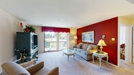 Located at 1600 Pointe Dr in Valparaiso, Indiana, this single-floor residence offers a well-organized layout designed for comfortable everyday living. The living room serves as the heart of the home, featuring plush carpeting, a bold burgundy accent wall, and a sliding glass door that opens to a private balcony with outdoor seating and views of the surrounding greenery, allowing abundant natural light to fill the space. The living area flows seamlessly into a dedicated dining room, also accented by a rich burgundy wall, a ceiling fan with light fixture, and ample room for a full dining set. The kitchen is efficiently designed with warm honey-toned wood cabinetry, light countertops, a white tile backsplash, tile flooring, and stainless steel appliances including a dishwasher. Two carpeted bedrooms provide comfortable retreats, each offering generous closet storage. One bedroom includes dual closets and a dedicated desk area, ideal for a home office setup. The two bathrooms are well-appointed — one features tile flooring with a shower-tub combination, while the second includes a walk-in shower and a large vanity mirror. Throughout the residence, a cohesive warm color palette and consistent finishes create a welcoming and functional living environment.