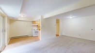 Located at 2568 Western Ave in Altamont, NY, this one-bedroom, one-bathroom residence offers a well-organized single-floor layout with a comfortable and functional design. The living areas are divided into two connected spaces, providing flexibility for both relaxing and entertaining. A standout feature is the full brick fireplace with a raised hearth in one of the living areas, adding warmth and classic character to the space. A large window allows natural light to fill the room, creating an inviting atmosphere. The second living area transitions seamlessly toward the kitchen, which features light wood cabinetry, a white range, and hardwood-style flooring that contrasts with the soft carpet throughout the main living spaces. Sliding glass doors in one of the living areas open to a private balcony overlooking lush greenery. The generously sized bedroom is carpeted and includes a large window framing outdoor views, a dedicated closet, and baseboard heating. The bathroom is clean and classic, featuring a full tub-shower combination with tiled surround and a distinctive mosaic tile floor. A thermostat and baseboard heating system are present throughout, ensuring year-round comfort. The neutral color palette and open flow make this a versatile and welcoming space.