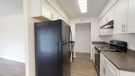 Located at 1201 Seminole Blvd in Largo, Florida, this single-floor residence offers a thoughtfully laid-out interior with a clean, updated aesthetic throughout. The galley-style kitchen is well-appointed with white shaker cabinetry, dark granite-style countertops, black appliances including a full-size refrigerator and electric range, and wood-look vinyl plank flooring. Overhead lighting keeps the space bright and functional.

The open living and dining area features the same durable wood-look flooring, a ceiling fan with light fixture, and a window fitted with blinds that allows natural light to filter in. A sliding glass door with vertical blinds provides additional light and access to the exterior. The living space flows naturally from the kitchen, creating a cohesive and connected common area.

The bedrooms are finished with plush wall-to-wall carpet, neutral walls, and windows with blinds. At least one bedroom includes a sliding closet with built-in shelving for storage.

The bathrooms are neatly finished with white cabinetry, marble-look countertops, brushed nickel hardware, and wood-look flooring. One bathroom features a full tub and shower combo with a large vanity mirror, while a second bathroom offers a single vanity with sink. Throughout, the space maintains a bright, neutral palette and move-in ready condition.