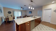 Located at 20 House Ave in Camp Hill, PA, this single-floor residence offers a well-designed open-concept layout that seamlessly connects the kitchen, dining, and living areas. The kitchen is a standout feature, showcasing rich walnut-toned cabinetry, white quartz countertops, a large center island with an undermount sink and stainless steel dishwasher, and stainless steel appliances including an electric range and over-the-range microwave. Stylish pendant lighting hangs above the island, complementing the hardwood flooring found in the kitchen area. The open living room is bright and inviting, featuring crown molding, a ceiling fan, and sliding glass doors with vertical blinds that allow ample natural light to fill the space. The bedroom is generously sized with plush carpeting, a ceiling fan, and a window that adds to the airy feel of the room. The bathroom is tastefully appointed with rich wood vanity cabinetry, white quartz countertops, a modern vessel sink, a framed mirror, tile flooring, and a shower/tub combination. Throughout the residence, neutral warm tones and consistent finishes create a cohesive and comfortable living environment.