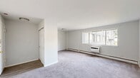 Located at 4214 Longshore Ave in Philadelphia's 19135 neighborhood, this one-bedroom, one-bathroom unit is thoughtfully designed to maximize its compact footprint. The layout flows from a welcoming entrance into a combined living and dining area, where soft wall-to-wall carpeting, neutral white walls, and large windows allow natural light to fill the space. A wall-mounted air conditioning unit and baseboard heating ensure year-round comfort in the living room, which also features a closet near the entry. The kitchen connects conveniently to the dining area and features hard-surface flooring, offering a practical contrast to the carpeted main living spaces. The generously sized bedroom provides ample room for furnishings and is outfitted with a double-door closet offering substantial storage, along with a window that brings in natural light. The clean, white bathroom includes a vanity with under-sink cabinetry, a mirrored medicine cabinet, and a shower/tub combination, all set on wood-look vinyl flooring. With two closets throughout the unit, practical storage is well accounted for. The overall aesthetic is clean, bright, and move-in ready, presenting a functional and comfortable living space.