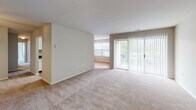This single-floor unit at 5731 Magnolia Tree Ct in Frederick, Maryland is designed with a practical, open layout that connects the main living areas seamlessly. The living room is generously sized, featuring neutral-toned carpet, bright white walls, and large sliding glass doors fitted with vertical blinds that allow abundant natural light and outdoor views. An adjacent dining area with hardwood-style flooring and a classic chandelier connects directly to the kitchen.

The kitchen is well-equipped with white cabinetry, dark granite-style countertops, hardwood-style flooring, a coil electric range, refrigerator, and dishwasher. A set of louvered bifold doors provides additional storage space within the kitchen area.

The bedrooms are carpeted and bright, with large windows offering natural light and views of surrounding greenery. Each bedroom includes closet space, with at least one featuring a walk-in closet. The bathrooms are clean and functional, each featuring a white tiled tub-shower combination, chrome fixtures, and neutral wall tones. Throughout the unit, the consistent use of neutral colors and natural light creates a calm, welcoming atmosphere.