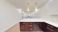 Located at 523 Wheelers Farms Rd in Milford, CT, this well-appointed 3-bedroom, 2-bathroom unit offers a thoughtfully designed single-floor layout with generous living space. Light wood-tone flooring runs throughout, complementing the bright, white walls and recessed lighting found in every room.

The kitchen is a standout feature, showcasing rich dark-wood lower cabinetry paired with crisp white upper cabinets, a herringbone-patterned tile backsplash, quartz countertops, and a full suite of stainless steel appliances including a French door refrigerator, range, dishwasher, and microwave. A large central island with pendant lighting connects seamlessly to the open living area, which is finished with crown molding and recessed lighting.

The primary bedroom is generously sized, featuring a tray ceiling with crown molding, a wide triple window with views to the exterior, and a wall-mounted HVAC unit. Additional bedrooms are bright and well-proportioned, each with natural light from windows fitted with blinds. The bathrooms are elegantly finished with large-format marble-look tile flooring and a glass-enclosed shower. A hallway utility area houses a stacked washer and dryer for added convenience. Two closets and four hallways round out this highly functional layout.
