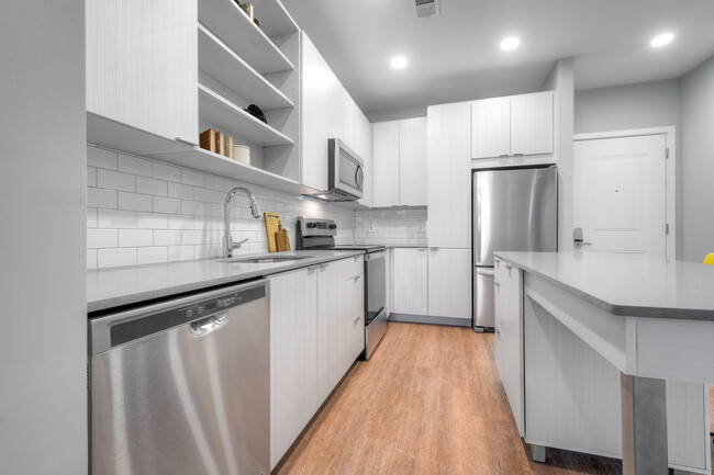 Cocina con encimeras de piedra de cuarzo y gabinetes blancos con placa para salpicaduras de azulejos en pisos de superficie dura - Kanso Twinbrook