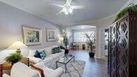 This single-floor residence offers a thoughtfully designed layout that combines comfort and functionality throughout. The living room serves as the heart of the home, featuring crown molding, a ceiling fan, warm neutral-toned walls, and hardwood-style flooring. A graceful arched opening connects the living room to a bright, window-lined sitting room, allowing generous natural light to flow through both spaces and creating an open, airy feel.

The entryway is welcoming and practical, with hardwood-style floors, a console table area, and direct access to the dining space, which is accented with track lighting and crown molding.

The kitchen is efficiently laid out with white cabinetry, ample counter space, and full appliances including an electric range and built-in microwave, making it well-equipped for everyday use.

Both bedrooms are comfortably sized, carpeted, and fitted with ceiling fans and windows that invite natural light. Each room offers a calm retreat-like atmosphere.

The bathrooms are clean and functional; the primary bath features a double-sink vanity with a large mirror, hardwood-style flooring, and a shower-tub combination, while the secondary bath includes a tub-shower and access to a walk-in closet. Together, these spaces offer practical storage and convenience throughout the residence.