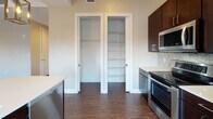 Located at 251 Main St in the heart of downtown Buffalo, NY, this modern single-floor residence offers a thoughtfully designed layout with contemporary finishes throughout. Rich dark hardwood flooring flows seamlessly across the entire space, creating a warm and cohesive aesthetic.

The open-concept living and dining area is bathed in natural light through large windows fitted with roller shades, framing impressive views of Buffalo's iconic downtown architecture. Recessed lighting adds to the bright, airy ambiance. The space transitions effortlessly into a well-appointed kitchen featuring dark espresso cabinetry, light quartz countertops, a mosaic tile backsplash, stainless steel appliances, and a breakfast bar with pendant lighting. Ample built-in storage is provided by a dedicated pantry and coat closet adjacent to the kitchen.

The bedrooms are generously proportioned, each offering natural light through framed windows and access to closet space, with one bedroom featuring a walk-in closet. The neutral warm-toned walls lend a calm, inviting feel throughout.

Two bathrooms serve the unit — one featuring a glass-enclosed walk-in shower with tile surround and a dark vanity, and a second half bath finished with consistent modern fixtures. The overall design reflects clean lines, quality materials, and a polished urban aesthetic suited to downtown living.