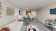 This well-appointed two-bedroom, two-bathroom residence at 1800 Palmer Rd, Unit 215 in Fort Washington, Maryland offers a comfortable and functional single-floor layout. The inviting living room is filled with natural light streaming through large windows dressed with sheer curtains, creating a bright and airy atmosphere. Plush carpeting flows throughout the main living areas and bedrooms, adding warmth underfoot. Adjacent to the living room, a dedicated dining area connects seamlessly to the kitchen, which features warm wood cabinetry, granite-style countertops, light wood-style flooring, and a full suite of stainless steel appliances including a refrigerator, range, microwave, and dishwasher. The spacious primary bedroom offers a generous footprint with a large window providing natural light, and direct access to a private en-suite bathroom. The en-suite features a tiled walk-in shower, a single vanity with ample cabinet storage, and clean, neutral finishes. The second bedroom is carpeted and well-lit with its own window. A second full bathroom with tile flooring, a vanity, and a shower-tub combination serves the additional bedroom. A closet completes the layout, providing convenient storage within this thoughtfully designed residence.