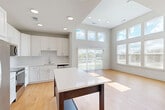 Located at 2320 Clubhouse Station Pl in Waldorf, MD, this well-designed single-floor, 3-bedroom, 2-bathroom home offers a clean, modern aesthetic throughout. The open-concept layout seamlessly connects the kitchen, dining, and living areas into one bright, expansive space. The kitchen is outfitted with crisp white shaker cabinetry, quartz countertops, a central island, and a full suite of stainless steel appliances including a refrigerator, range, microwave, and dishwasher. The living and dining area is bathed in natural light from a generous wall of windows and a sliding glass door, complemented by soaring ceilings with clerestory windows that amplify the sense of openness. Warm hardwood-style flooring runs throughout the main living spaces and bedrooms, creating a cohesive and inviting atmosphere. The primary bedroom features elevated ceilings, large windows with outdoor views, and access to well-organized closet space. Two additional bedrooms offer comfortable accommodations, each with their own closet. The bathrooms are finished with tile surround tub-shower combinations and neutral tones. A dedicated laundry area and five closets provide ample storage throughout. Recessed lighting and neutral wall tones complete the home's clean, contemporary feel.