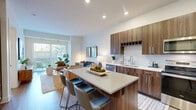 Located at 3250 W 66th St in Edina, MN, this thoughtfully designed one-bedroom, one-bathroom residence offers a efficient yet comfortable layout across a single floor. The open-concept living and kitchen area serves as the heart of the home, bathed in natural light from large sliding glass doors that lead to an outdoor space with views of surrounding greenery. The living area features clean white walls, light wood-style flooring, and ample room for relaxed seating arrangements. The kitchen is a standout feature, showcasing rich walnut-toned cabinetry reaching to the ceiling, a herringbone tile backsplash, stainless steel appliances including a refrigerator, range, microwave, and dishwasher, and a central island with bar seating — ideal for both cooking and casual dining. The bedroom offers a calm, well-lit retreat with a natural window, carpeted flooring, and direct access to a dedicated closet. The bathroom is finished with wood-grain cabinetry, a white quartz countertop, a tub-shower combination with tile surround, and light wood-style flooring, creating a cohesive and modern aesthetic. Throughout the unit, the design strikes a balance between contemporary style and everyday functionality.
