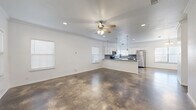 This well-appointed two-story home offers four bedrooms and five bathrooms across two generously sized floors. The main level makes a strong first impression with its striking polished concrete floors, which extend throughout the open-concept living, dining, and kitchen areas. Crown molding and ceiling fans add refined detail to the bright, airy living room, which is bathed in natural light from multiple windows fitted with clean white blinds.

The kitchen is a functional highlight, featuring white shaker cabinetry, a gray subway tile backsplash, granite-look countertops, stainless steel appliances, and elegant pendant lighting over the breakfast bar. A pantry provides additional storage, complementing the kitchen's ample cabinet space.

Upstairs, the four bedrooms offer a comfortable retreat, each carpeted for warmth and equipped with ceiling fans. The generously sized primary bedroom includes a walk-in closet with built-in shelving and hanging rods. The five bathrooms are finished with gray vanities and polished fixtures, including polished concrete flooring in at least one bathroom.

A dedicated laundry room houses a full-size washer and dryer with overhead shelving. Additional highlights include a balcony, multiple staircases, and five closets throughout the home, ensuring abundant storage and a practical, well-organized layout.