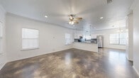 This well-appointed two-story home offers four bedrooms and five bathrooms across two generously sized floors. The main level makes a strong first impression with its striking polished concrete floors, which extend throughout the open-concept living, dining, and kitchen areas. Crown molding and ceiling fans add refined detail to the bright, airy living room, which is bathed in natural light from multiple windows fitted with clean white blinds.

The kitchen is a functional highlight, featuring white shaker cabinetry, a gray subway tile backsplash, granite-look countertops, stainless steel appliances, and elegant pendant lighting over the breakfast bar. A pantry provides additional storage, complementing the kitchen's ample cabinet space.

Upstairs, the four bedrooms offer a comfortable retreat, each carpeted for warmth and equipped with ceiling fans. The generously sized primary bedroom includes a walk-in closet with built-in shelving and hanging rods. The five bathrooms are finished with gray vanities and polished fixtures, including polished concrete flooring in at least one bathroom.

A dedicated laundry room houses a full-size washer and dryer with overhead shelving. Additional highlights include a balcony, multiple staircases, and five closets throughout the home, ensuring abundant storage and a practical, well-organized layout.