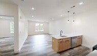 This thoughtfully designed one-bedroom, one-bathroom unit at 448 S Orange Ave in Newark, NJ offers a clean, modern aesthetic with high-quality finishes throughout. The open-concept kitchen and living area serves as the heart of the unit, anchored by a striking kitchen island topped with white marbled quartz countertops. The kitchen is well-appointed with warm wood cabinetry, contrasting grey lower cabinets, stainless steel appliances including a gas range, microwave, and refrigerator, and a classic white subway tile backsplash. Pendant lighting adds a contemporary touch above the island. Consistent light-toned wood-look flooring flows seamlessly through every room, enhancing the bright, cohesive feel of the space. The bedroom is generously proportioned, featuring a large double-door closet with sleek matte black hardware and a window that fills the room with natural light. The full bathroom is finished to a high standard, showcasing marble-look tile walls in the shower/tub area, a floating white vanity with a matte black faucet, a framed mirror, and neutral floor tiles. Recessed lighting throughout the unit maintains a clean ceiling line, and crisp white walls create a fresh, versatile backdrop ready for personalization.