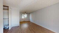 Located at 3685 S Bascom Ave in Campbell, California, this single-floor residence offers a clean, modern aesthetic with a bright and cohesive design throughout. The living area is spacious and open, featuring warm hardwood-style flooring, light gray walls, and a textured ceiling. A ceiling fan with a light fixture provides both comfort and functionality, while large windows frame views of surrounding mature trees, filling the space with abundant natural light. A wall-mounted baseboard heater and an in-wall AC unit ensure year-round climate control. The galley-style kitchen is efficiently designed with white shaker cabinetry extending to the ceiling, sleek white countertops, a stainless steel sink, and stainless steel appliances including a refrigerator and range. A skylight-style ceiling fixture brightens the workspace, and the light wood flooring continues seamlessly from the main living areas. The bathroom is clean and contemporary, featuring a white vanity with ample counter space, a tub-shower combination with a curtain rod, and a small transom window that brings in natural light while maintaining privacy. The flooring carries the same warm wood-look tone. The bedroom is carpeted for comfort and features a wide picture window overlooking lush greenery, creating a serene and restful atmosphere. Baseboard heating is also present in the bedroom, ensuring consistent warmth throughout the unit.