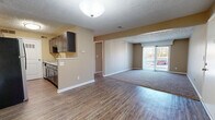 This well-appointed 1-bedroom, 1-bathroom unit is thoughtfully laid out across a single floor, offering a comfortable and efficient use of space. The entry opens into a hardwood-style vinyl flooring area that transitions seamlessly into the combined living and dining space. Warm beige walls and textured ceilings carry throughout the unit, creating a consistent and neutral aesthetic.

The kitchen features dark cabinetry with light stone-look countertops, a stainless steel refrigerator, and matching appliances, including a range and microwave. The kitchen flows openly toward the living area, making it ideal for everyday functionality. A dedicated entry door from the kitchen provides convenient access.

The living room is carpeted and generously sized, with a sliding glass door that opens to a private balcony, allowing natural light to fill the room and offering pleasant outdoor views. A second carpeted area adjacent to the living space provides additional flexibility.

The bedroom is a comfortable size, featuring carpet flooring, a window with blinds for natural light and privacy, and a textured ceiling. A dedicated closet provides ample storage. The full bathroom includes a clean, white tub-shower combination with brushed nickel fixtures. The unit also benefits from a separate closet space for additional storage needs.