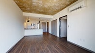 Located at 1828 N Farwell Ave in Milwaukee's vibrant East Side neighborhood, this single-floor unit blends industrial and contemporary design elements throughout. The open-concept living area immediately draws attention with its striking exposed concrete ceiling, which adds raw, urban character and contrasts handsomely with the clean white walls and rich, dark hardwood flooring that extends throughout the space.

The kitchen is thoughtfully integrated into the main living area and features white cabinetry, a subway tile backsplash, granite countertops, stainless steel appliances including a refrigerator and dishwasher, and a peninsula with pendant lighting overhead. The layout encourages both everyday functionality and effortless entertaining.

A wall-mounted mini-split HVAC unit ensures year-round comfort. Modern sliding and hinged doors with dark trim lead to additional rooms and closet storage, maintaining a cohesive aesthetic throughout.

The bedroom is generously sized, featuring the same exposed concrete ceiling and dark hardwood floors, and opens directly to a private balcony with impressive views of the Milwaukee skyline, allowing abundant natural light to fill the room.

The bathroom is clean and efficiently designed with a walk-in shower, granite-topped vanity with white cabinetry, and wood-look flooring, completing this polished urban residence.