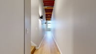 Located at 425 W Lakeside Ave in Cleveland's vibrant Lakeside neighborhood, this one-bedroom, one-bathroom loft-style unit masterfully blends industrial character with modern finishes. The open-concept kitchen and living area serves as the heart of the space, showcasing soaring exposed wood beam ceilings supported by original timber columns — a striking nod to the building's historic origins. Light hardwood flooring runs throughout, complementing the whitewashed brick walls that add texture and warmth. Large arched and rectangular windows flood the living area with abundant natural light.

The kitchen is well-appointed with white shaker cabinetry, a white quartz peninsula with bar seating, subway tile backsplash, and a full suite of stainless steel appliances. An in-unit washer is conveniently integrated into the kitchen island cabinetry. A hallway with exposed beam ceiling detail leads to the private bedroom, which features windows along one wall and continued hardwood flooring. Two closets provide ample storage. The bathroom includes a full tub/shower combination with clean, modern fixtures. The overall ambiance is a refined industrial aesthetic — open, airy, and full of character unique to Cleveland's adaptive reuse architecture.
