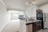 Located at 1069 Chateau Crossing Dr in Fort Mill, SC, this well-appointed single-floor home offers three bedrooms and two bathrooms across a comfortable and efficiently designed floor plan. The open-concept kitchen and living area serves as the heart of the home, featuring a peninsula with granite countertops, dark espresso cabinetry, stainless steel appliances, and hardwood-style flooring. An elegant arched passageway connects the kitchen to the carpeted living room, which is accented with crown molding and filled with natural light from a front-facing window. The spacious primary bedroom enjoys generous proportions, plush carpet, crown molding, and a large window with views of the surrounding neighborhood. The additional bedrooms are bright and well-sized, each with soft carpet and natural light filtering through window blinds. Both bathrooms are clean and functional, with the full bath showcasing a dark vanity, wood-look tile flooring, and a tub-shower combination. A dedicated laundry room with built-in shelving adds everyday convenience. The home's neutral color palette and consistent finishes throughout create a cohesive and welcoming atmosphere.