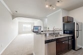Located at 1069 Chateau Crossing Dr in Fort Mill, SC, this well-appointed single-floor home offers three bedrooms and two bathrooms across a comfortable and efficiently designed floor plan. The open-concept kitchen and living area serves as the heart of the home, featuring a peninsula with granite countertops, dark espresso cabinetry, stainless steel appliances, and hardwood-style flooring. An elegant arched passageway connects the kitchen to the carpeted living room, which is accented with crown molding and filled with natural light from a front-facing window. The spacious primary bedroom enjoys generous proportions, plush carpet, crown molding, and a large window with views of the surrounding neighborhood. The additional bedrooms are bright and well-sized, each with soft carpet and natural light filtering through window blinds. Both bathrooms are clean and functional, with the full bath showcasing a dark vanity, wood-look tile flooring, and a tub-shower combination. A dedicated laundry room with built-in shelving adds everyday convenience. The home's neutral color palette and consistent finishes throughout create a cohesive and welcoming atmosphere.