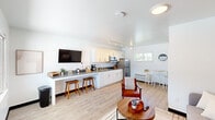 Located at 4711 University Ave in Cedar Falls, Iowa, this thoughtfully designed studio makes excellent use of its compact footprint across a single floor. The open-concept layout seamlessly integrates the kitchen and living area, creating a functional and cohesive space filled with natural light from multiple windows.

The kitchen is outfitted with crisp white cabinetry, gray stone countertops, stainless steel appliances including a full-size refrigerator and microwave, and a double-basin sink. A breakfast bar with bar stools provides casual seating, while a wall-mounted flat-screen TV adds convenience. Track lighting overhead illuminates the space efficiently. A small dining nook with a bistro-style table and stools is positioned near a window with a pleasant outdoor view.

The living area features a murphy bed integrated into a built-in wall unit with open shelving above, doubling as a sofa when closed — a smart space-saving solution. Light wood-look flooring flows throughout, complementing the clean white walls and modern aesthetic.

The bathroom is bright and well-appointed, featuring a white vanity with gray stone countertop, an undermount sink, a large mirror, and a window that brings in natural light. The overall ambiance throughout the space is clean, modern, and efficiently organized, making it an ideal compact living solution.