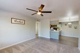 Located at 10615 Meadowglen Ln in Houston, TX, this single-floor residence offers a practical and comfortable layout with 2 bedrooms, 2 bathrooms, a dedicated laundry room, and ample closet space. The open-concept living and dining area is finished with plush carpeting and features a ceiling fan with light fixture, creating a bright and airy atmosphere. The kitchen is equipped with grey cabinetry, white quartz-style countertops, black appliances including an electric range and refrigerator, and a mosaic tile backsplash. A peninsula counter connects the kitchen to the living and dining areas, enhancing the open flow. A pantry provides additional storage convenience. Both bedrooms are carpeted and include ceiling fans; natural light filters in through windows with outdoor views. Each bedroom is served by a dedicated closet. The two full bathrooms feature tub-shower combinations, vanities with light countertops, and wood-look flooring, maintaining a clean, neutral aesthetic throughout. Hallways connect the rooms efficiently, and the included laundry room adds everyday functionality. The overall palette of soft greys and whites lends the space a modern, cohesive feel.