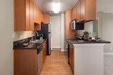 Located on Lake Murray Boulevard in La Mesa, California, this two-bedroom, two-bathroom residence offers a thoughtfully arranged single-floor layout with a comfortable sense of space throughout. The combined kitchen and dining area is a functional highlight, featuring warm wood cabinetry, dark granite countertops, hardwood-style flooring, and a peninsula breakfast bar — all complemented by stainless steel appliances including a refrigerator, dishwasher, and range. A ceiling fan in the adjoining dining area adds to the airy feel of the open layout. The living room is carpeted and opens directly onto a private balcony through sliding glass doors, offering pleasant views of surrounding greenery and natural light. Both bedrooms are carpeted with neutral tones, offering a calm and restful atmosphere. The primary bedroom features sliding closet doors and a dedicated en-suite bathroom with a granite-topped vanity, hardwood-style flooring, and a combined tub and shower. The second bedroom benefits from natural light through a window with outdoor views. Four total closets provide generous storage throughout. An in-unit laundry area adds everyday convenience, completing this well-appointed La Mesa residence.