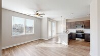 Located at 5220 Center St in Williamsburg, VA, this 2-bedroom, 2-bathroom home offers a thoughtfully designed single-floor layout with modern finishes throughout. The open-concept kitchen and living area serves as the heart of the home, bathed in natural light from multiple windows and a glass-panel door. The kitchen is well-equipped with rich dark-toned cabinetry, granite countertops, stainless steel appliances, and a peninsula island with pendant lighting overhead — ideal for both cooking and casual dining. Light hardwood-style flooring and a ceiling fan complete the living space. A well-lit hallway connects the main living area to the private quarters, featuring built-in shelving for added storage. Both bedrooms offer plush carpeting, ceiling fans, and natural light from exterior windows. The primary bathroom includes a walk-in glass-enclosed shower, while the second bathroom features a full soaking tub with tiled surround — both finished with granite-topped vanities and wood-toned cabinetry. Three closets and a dedicated laundry area provide ample storage and everyday convenience. The neutral color palette and clean architectural lines give the home a bright, move-in-ready feel.