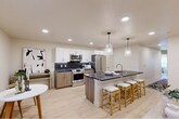 Located at 805 Roosevelt in Boise, Idaho, this thoughtfully designed 2-bedroom, 2-bathroom residence offers a seamless single-level layout with contemporary finishes throughout. The heart of the home is an expansive open-concept living, dining, and kitchen area anchored by light hardwood flooring and recessed lighting. The chef's kitchen is a standout feature, showcasing white upper cabinetry, warm wood lower cabinets, a bold dark marble-topped island with seating for multiple guests, stainless steel appliances, a dark tile backsplash, and elegant pendant lighting. The primary bedroom is a serene retreat with plush carpeting and a well-appointed en-suite bathroom featuring full-height marble tile, a glass-enclosed walk-in shower with built-in niche, and access to a walk-in closet. The second bedroom offers direct access to the patio through a glass door, filling the room with natural light, and includes a wall-mounted climate control unit. The private patio features exposed brick columns and glass railing with views of the surrounding neighborhood. Additional highlights include an in-unit laundry, pantry, and ample closet storage throughout.