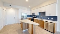 Located at 2500 SW 22nd Terrace in Fort Lauderdale, FL, this one-bedroom, one-bathroom residence offers a well-designed layout across a single floor. Neutral large-format tile flooring flows consistently throughout the space, lending a clean, cohesive aesthetic.

The kitchen is a standout feature, boasting a two-tone design with crisp white upper cabinetry and warm wood-toned lower cabinets, accented by a striking blue tile backsplash. A curved peninsula island with a light quartz countertop provides additional prep space and casual seating. Stainless steel appliances — including a French door refrigerator with ice maker, electric range, microwave, and dishwasher — complete the functional and stylish setup. Recessed lighting illuminates the space effectively.

The bedroom is a comfortable, well-proportioned room featuring a ceiling fan, natural light from a large window, and direct access to a spacious walk-in closet equipped with dual wire shelving systems for ample storage.

The bathroom offers a clean, modern design with a glass-enclosed walk-in shower adorned with large-format tile surround, and an additional storage closet within the room. Neutral tones and recessed lighting create a calm, functional atmosphere. A hallway connects the rooms efficiently, completing this thoughtfully laid-out Fort Lauderdale residence.