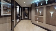 Located at 14909 Health Center Drive in Bowie, Maryland, this single-floor facility offers a thoughtfully designed suite of professional and communal spaces finished with a cohesive, upscale aesthetic throughout.

The library lounge serves as a warm, inviting retreat, lined floor-to-ceiling with built-in shelving stocked with books and decorative objects. Soft wall sconces, a circular pendant light, a cushioned window bench, a round accent table, and plush seating chairs create an atmosphere ideal for quiet reading or informal gatherings. A patterned geometric carpet anchors the room with a contemporary flair.

The business center provides a functional workspace equipped with multiple computer workstations, ergonomic task chairs, and built-in desks along the walls. Contemporary abstract artwork and textured wall finishes lend a polished look, while glass-paneled doors maintain visual connectivity to the adjacent corridor.

The conference room accommodates a full-sized rectangular table surrounded by upholstered chairs, complemented by a wall-mounted display, a classic landscape painting, dark wood cabinetry, and indoor greenery. Natural light filters in through a window, enhancing the professional atmosphere.

Connecting these spaces, the corridor features large-format tile flooring, decorative wall sconce panels with dramatic uplighting, and clean sightlines through glass-panel doors to the library and business center beyond.