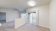Located on Riverstone Way in Columbus, Indiana, this two-story home offers a practical and well-appointed layout across two floors. The main living level comprises an open-plan living room, dining room, and kitchen. The living area features plush carpeting, a ceiling fan, and large windows that allow generous natural light to fill the space. A sliding glass door leads directly to a private balcony, extending the living area outdoors. The kitchen is equipped with white cabinetry, stainless steel appliances including a refrigerator and microwave, and a breakfast bar with a light countertop. The bedroom is a comfortable, carpeted room with a sizable window overlooking the surrounding neighborhood. The full bathroom features wood-look flooring, a wide vanity with white cabinetry and a large mirror, a soaking tub, and a separate shower. Abundant storage is provided throughout, with six closets including a spacious walk-in closet fitted with wire shelving. A dedicated laundry area adds everyday convenience. The lower level houses an attached garage with an automatic opener and additional storage potential. Carpeted stairs with a handrail connect the two floors. The home's neutral palette and clean finishes create a bright, move-in-ready atmosphere throughout.