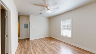 Located at 200 W Cranford Ave in Valdosta, Georgia, this single-story, 3-bedroom, 2-bathroom home offers a practical and well-appointed layout. The interior features warm wood-look laminate flooring throughout the bedrooms and living areas, complemented by light tile in the kitchen and bathrooms. Each bedroom is fitted with a ceiling fan and a window dressed with blinds, allowing natural light while maintaining privacy. The spacious primary bedroom provides a comfortable retreat with ample room and direct outdoor views. The kitchen is a functional highlight, showcasing white shaker-style cabinetry, granite countertops, tile flooring, and a full suite of stainless steel appliances including a range, microwave, dishwasher, and refrigerator. A dedicated laundry room with built-in wire shelving adds convenience to daily living. Both bathrooms are clean and straightforward, featuring tub/shower combinations with tile flooring. The home's neutral color palette of soft whites and warm wood tones creates a bright, cohesive atmosphere throughout. A dedicated entry door with classic panel detailing rounds out this efficient and move-in-ready home.
