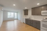 Located at 18730 Miner Ln in Morgan Hill, CA, this single-floor residence offers four bedrooms and three bathrooms with a clean, modern design throughout. Light wood-style flooring runs consistently across the home, creating a bright and cohesive aesthetic.

The open-concept kitchen is well-appointed with rich dark-toned cabinetry, white countertops, ample upper and lower cabinet storage, and white appliances including a range, microwave, refrigerator, and dishwasher. It flows naturally into the living area, which benefits from large windows and access to a private balcony, filling the space with natural light.

The spacious primary bedroom offers generous proportions and includes a walk-in closet with built-in wire shelving. Each bedroom is equipped with its own wall-mounted mini-split HVAC unit and programmable thermostat, providing individualized climate control. Bedrooms feature large windows that invite natural light and outdoor views.

The three bathrooms are finished in a clean, minimal style with light wood flooring, white subway-tiled tub-and-shower combinations, and grab bars for added accessibility. A dedicated laundry area rounds out the functional layout of this well-designed home.